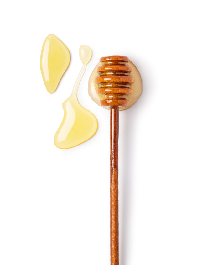 A wooden stick with honey on it next to some liquid.
